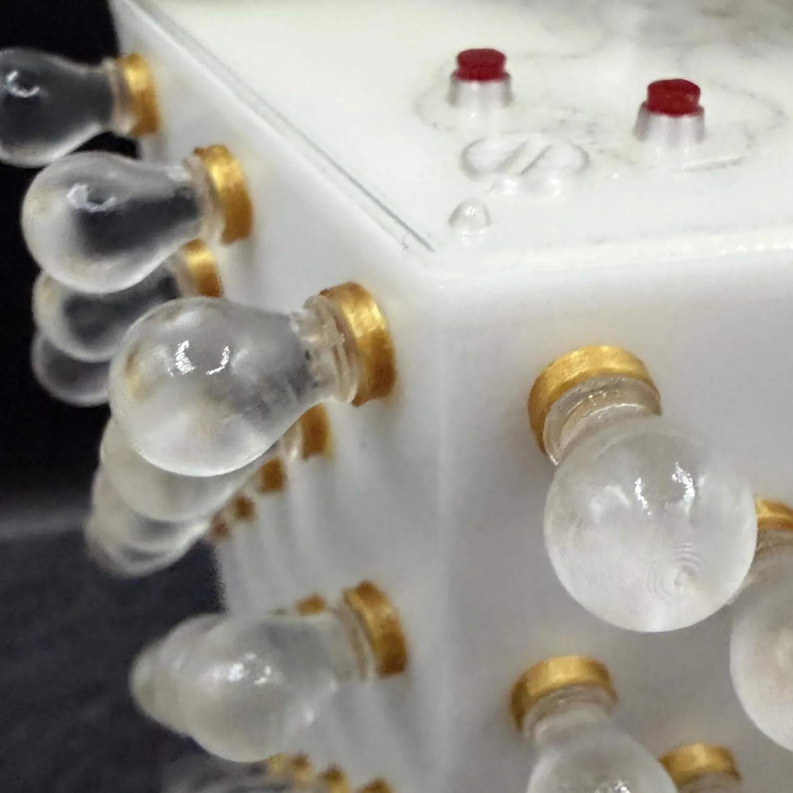 Close-up of the clear bulbs, gold-coloured fittings and red details on the base